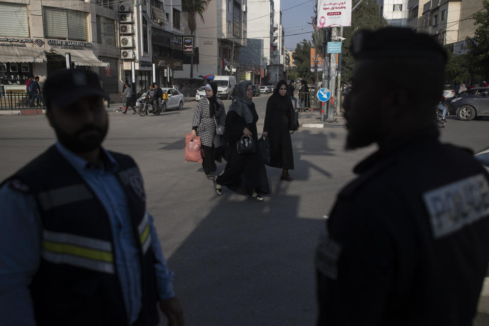 Palestinian women walk by two Hamas policemen in Gaza City, Thursday, Nov. 25, 2021. Gaza’s Hamas rulers collect millions of dollars a month in taxes and customs at a crossing on the Egyptian border – providing a valuable source of income that helps it sustain a government and powerful armed wing. After surviving four wars and a nearly 15-year blockade, Hamas has become more resilient and Israel has been forced to accept that its sworn enemy is here to stay. (AP Photo/ Khalil Hamra)