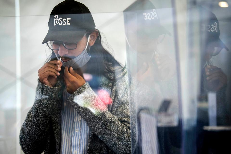 Manny Salas, 21, of Houston, administers his own COVID-19 test at Colby College in Waterville, Maine. Students must take two tests per week as part of the college's robust program.