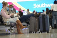 Travellers wait at the check-in counter for Southwest Airlines in the terminal of Denver International Airport Friday, Dec. 24, 2021, in Denver. More than 200 flights were cancelled by carriers out of Denver International because COVID-19 issues have created a shortage of workers. (AP Photo/David Zalubowski)