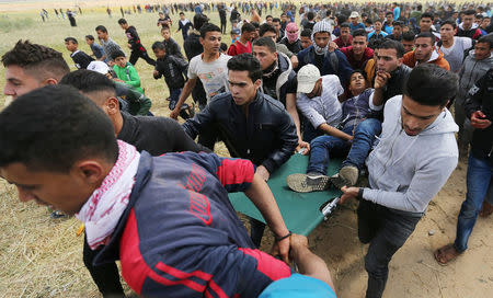 A wounded Palestinian is evacuated during clashes with Israeli troops, during a tent city protest along the Israel border with Gaza, demanding the right to return to their homeland, the southern Gaza Strip March 30, 2018. REUTERS/Ibraheem Abu Mustafa