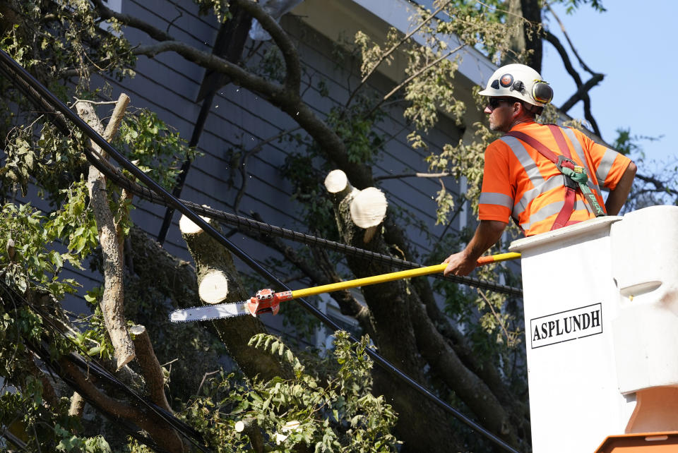 A worker trims a tree brunch around power line, Friday, Aug. 14, 2020, in Cedar Rapids, Iowa. The storm that struck Monday morning left tens of thousands of Iowans without power as of Friday morning. (AP Photo/Charlie Neibergall)