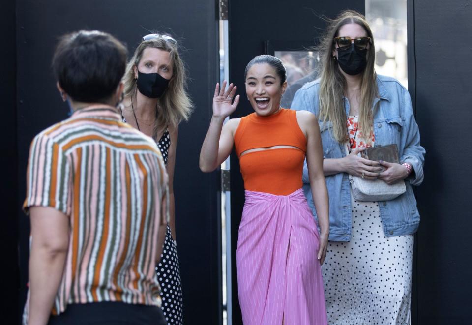 Unmasked "F9" actor Anna Sawai waves as she enters the arrivals carpet among masked people.