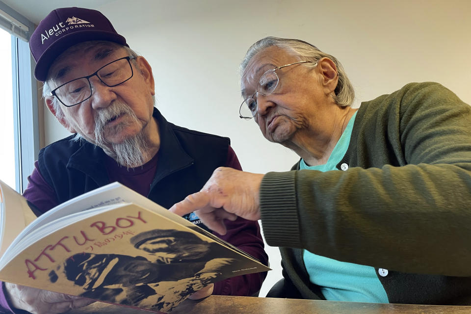 George Kudrin, left, and Pauline Golodoff look at a copy of the book "Attu Boy," Friday, Dec. 1, 2023, in Anchorage, Alaska. Gregory Golodoff, Pauline's late husband, and Elizabeth Golodoff Kudrin, George's late wife, were the last two living residents of Attu, Alaska, whose entire population was captured by the Japanese during World War II and sent to Japan until being liberated after the war. "Attu Boy" was written by Nick Golodoff, who was Gregory and Elizabeth's older brother. (AP Photo/Mark Thiessen)