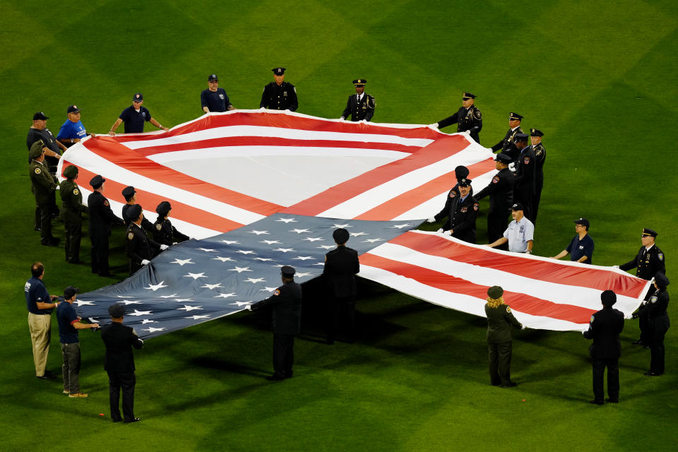 NEW YORK, NY - SEPTEMBER 11:  First responders are seen on the field holding an American Flag ribbon during the pre-game ceremony prior to the game between the New York Yankees and the New York Mets at Citi Field on Saturday, September 11, 2021 in New York, New York. (Photo by Daniel Shirey/MLB Photos via Getty Images)