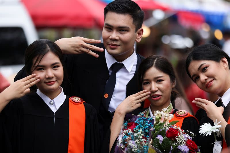 Students flash the three-fingers salute during a graduation ceremony, at Thammasat University in Bangkok