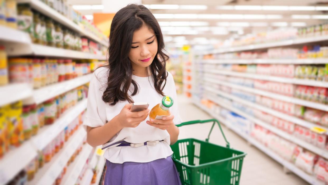 Young woman reading information about the product on the phone