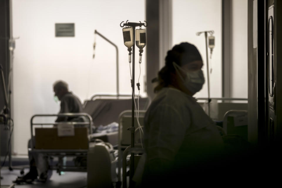 FILE - Seen through a plastic sheet a member of the medical staff checks on COVID-19 positive patients at the University Emergency Hospital waiting area, converted into a COVID-19 section due to the number of cases, in Bucharest, Romania, Monday, Nov. 8, 2021. (AP Photo/Vadim Ghirda, File)