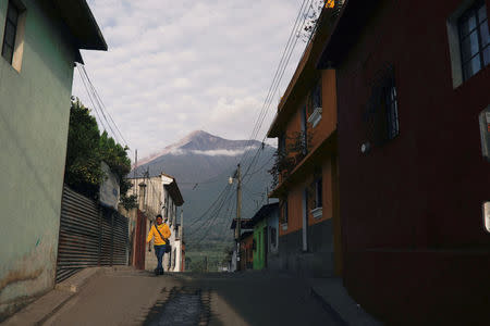A man walks along a street in front of Fuego volcano in Alotenango, Guatemala June 5, 2018. REUTERS/Jose Cabezas