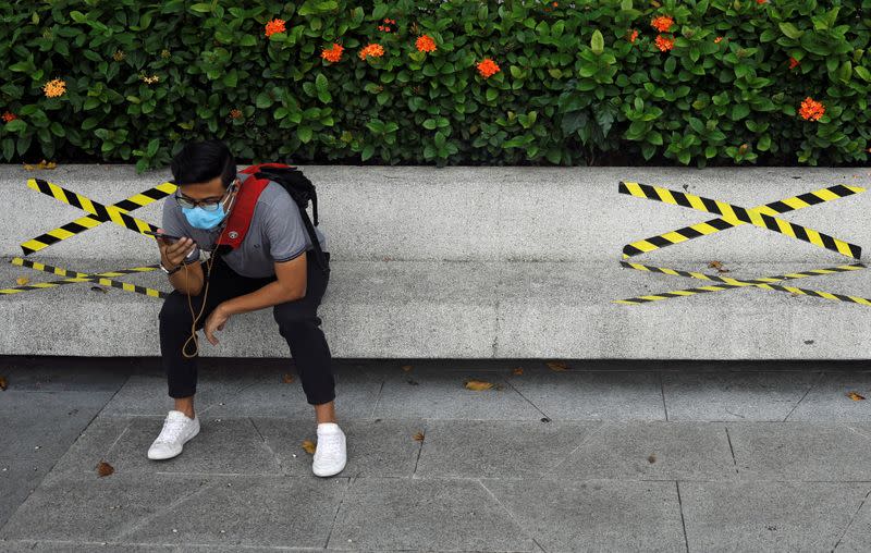 Man sits on a bench with distance markers along Marina Bay in Singapore