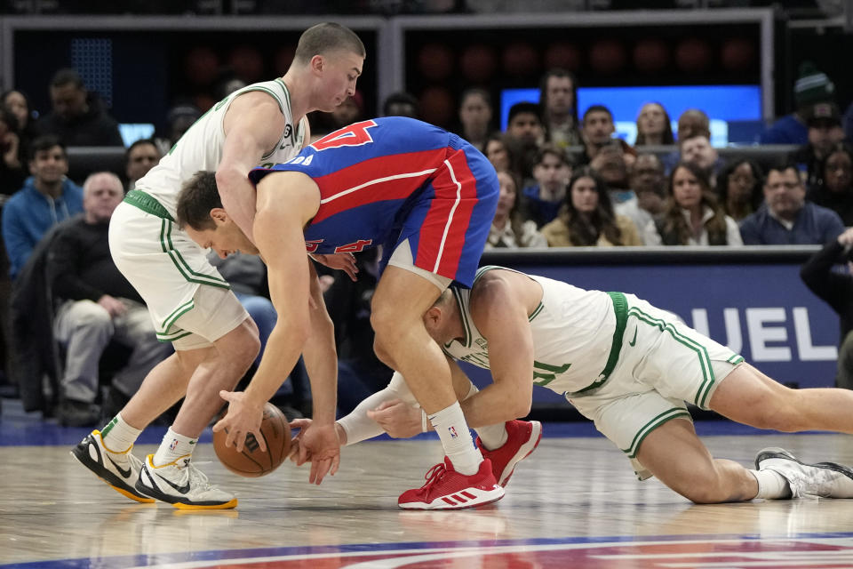 Boston Celtics guard Payton Pritchard, left, and Boston Celtics forward Blake Griffin reach in on Detroit Pistons forward Bojan Bogdanovic during the first half of an NBA basketball game, Monday, Feb. 6, 2023, in Detroit. (AP Photo/Carlos Osorio)