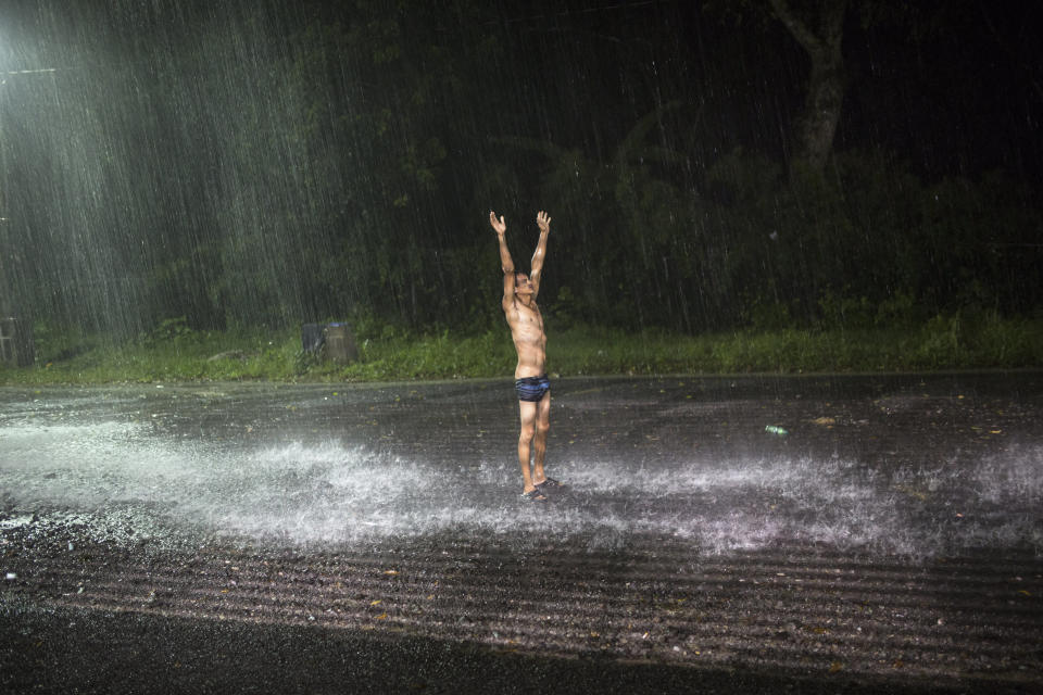 In this Nov. 4, 2018 photo, a man showers in the rain outside a temporary shelter set up for a splinter group of a migrant caravan hoping to reach the U.S. border, in Cordoba, Veracruz state, Mexico. Thousands of bone-tired Central Americans set their sights on Mexico City on Sunday after making a grueling journey through a part of Mexico that has been particularly treacherous for migrants seeking to get to the United States. (AP Photo/Rodrigo Abd)