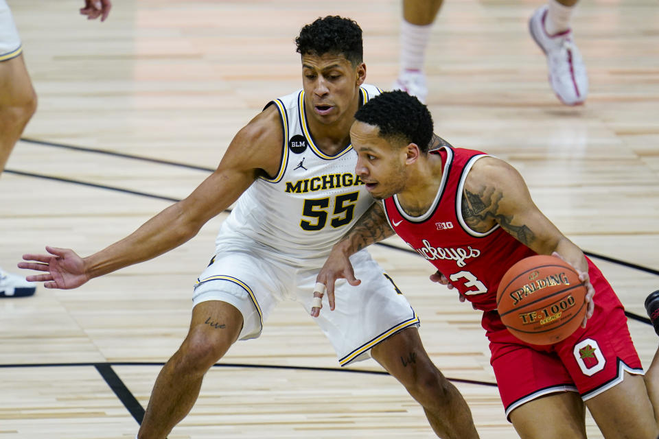 Ohio State guard CJ Walker (13) drives on Michigan guard Eli Brooks (55) in the first half of an NCAA college basketball game at the Big Ten Conference tournament in Indianapolis, Saturday, March 13, 2021. (AP Photo/Michael Conroy)