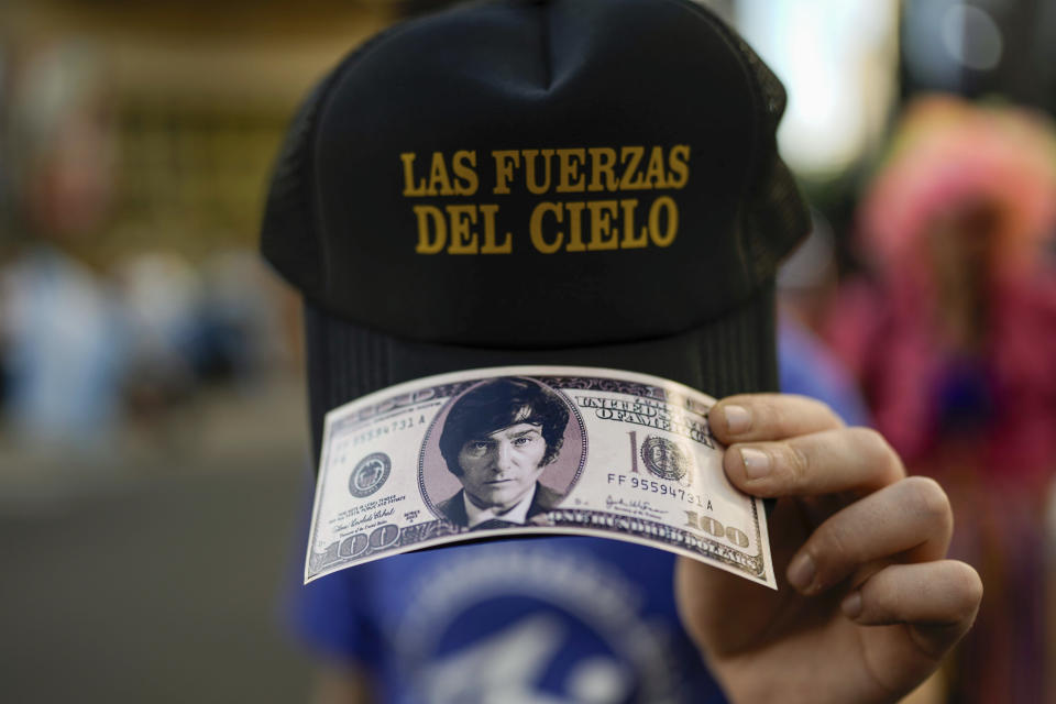 A supporter of the opposition presidential candidate Javier Milei holds a reproduction of a hundred dollar bill featuring the candidate's face outside his campaign headquarters after the polls closed in the presidential runoff election in Buenos Aires, Argentina, Sunday, Nov. 19, 2023. (AP Photo/Rodrigo Abd)