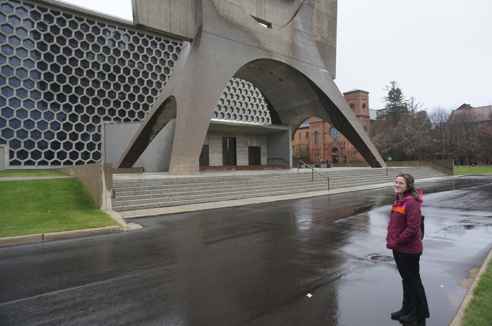 Margaret Nuzzolese Conway, director of campus ministry at Saint John's University, stands in front of the college's mid-20th century church in Collegeville, Minn., on Tuesday, Nov. 8, 2022. The campus ministry team at this Catholic college for men, and its twin institution for women, the College of Saint Benedict, has been trying to reach out to LGBTQ students, especially those striving to find ways "connecting God and sexuality," she said. (AP Photo/Giovanna Dell'Orto)