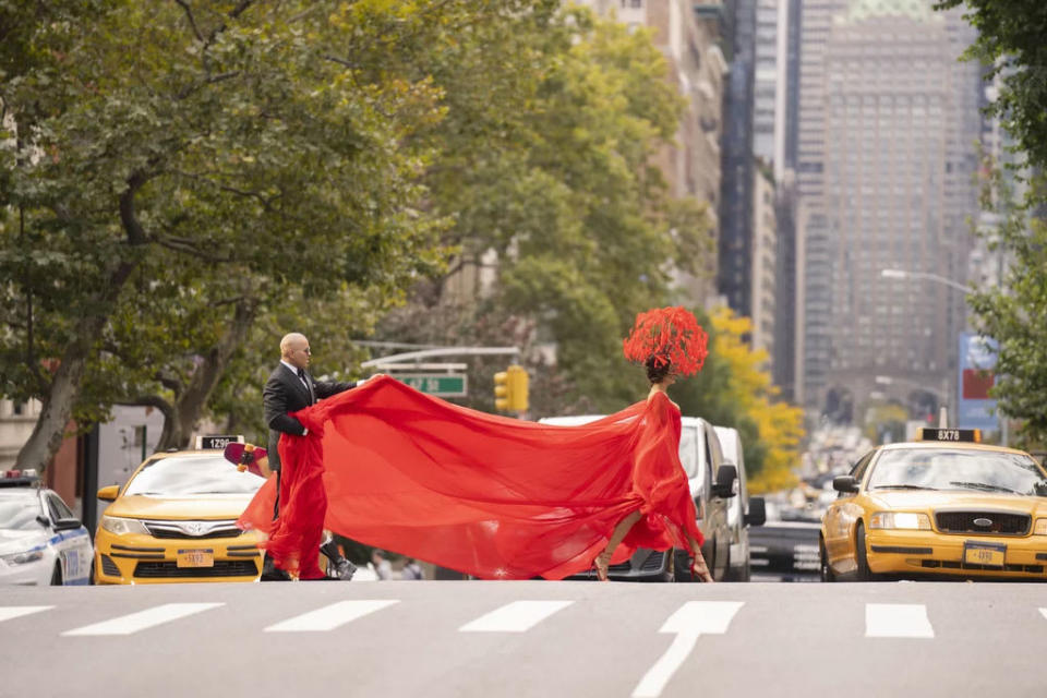 A still from And Just Like That showing Lisa Todd Wexley crossing 5th avenue in a flowing red dress.