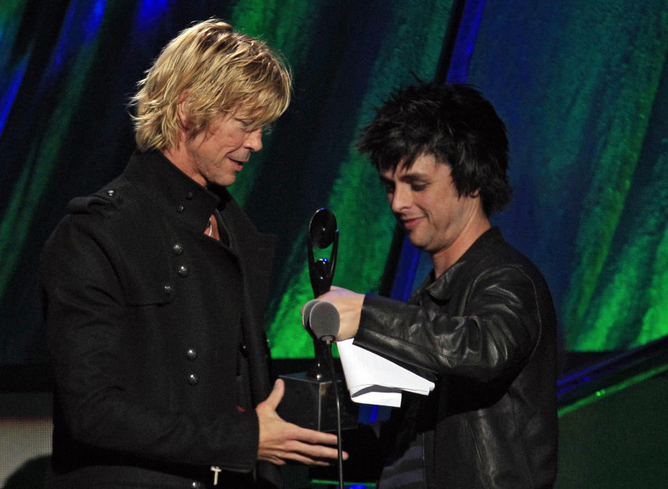 Guns N' Roses' Duff McKagan, left, accepts his trophy from Green Day's Billy Joe Armstrong after Guns N' Roses was inducted into the Rock and Roll Hall of Fame Saturday, April 14, 2012, in Cleveland. (AP Photo/Tony Dejak)