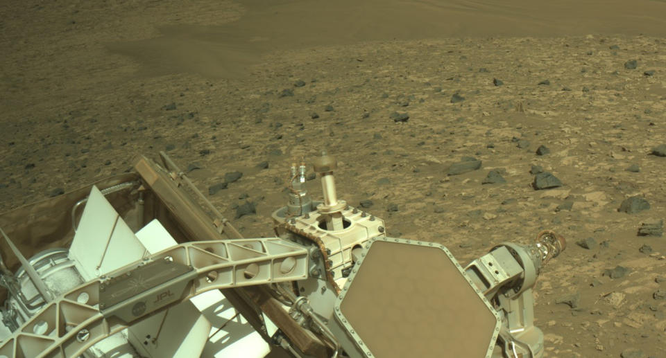 Part of the Perseverance rover is visible (left) as it takes a photo of the Jazero Crater Riverbed on the surface of Mars.