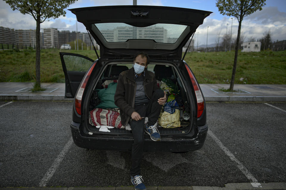 Juan Jimenez, 60, poses by his car which is now his home in Pamplona, northern Spain, Friday, March 19, 2021. Jimenez has been forced to dwell in his second-hand Ford for close to a year after seeing his life collapse when he and his wife bought a bigger house, only for mortgage payments to spiral out of control and for their marriage to crumble after the economic slowdown caused by the coronavirus pandemic destroyed his financial stability. (AP Photo/Alvaro Barrientos)