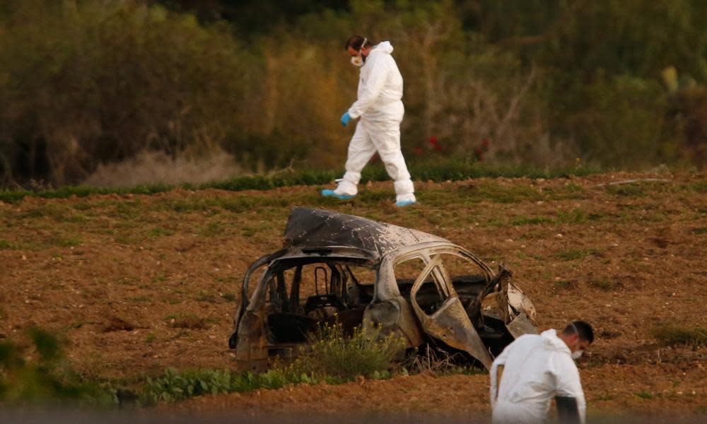 Forensic experts examine a field after a bomb blew up Daphne Caruana Galizia’s car.