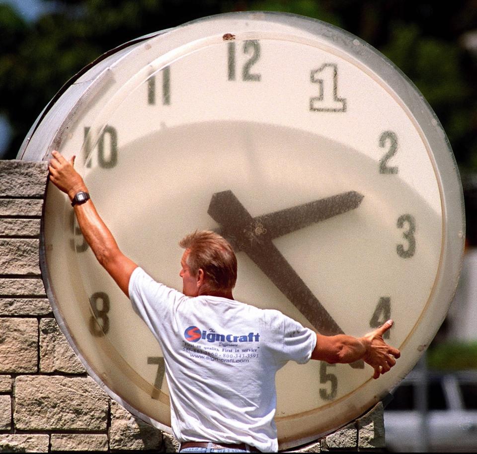 In this 1999 photo Joe Roskey works on the outdoor clock at the First Bank of Florida, at the corner of Olive Avenue and Southern Blvd.  Staff Photo by Lannis Waters