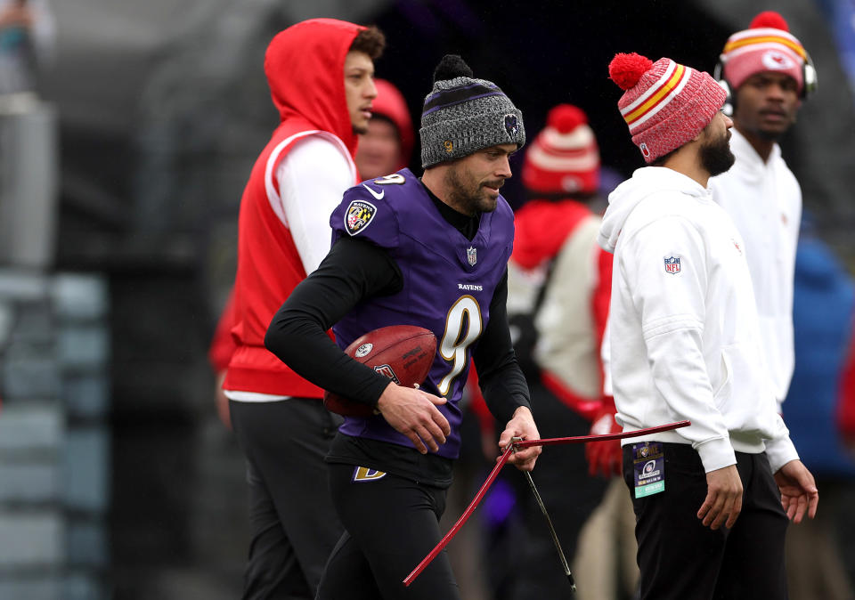  Justin Tucker carries his warmup equipment past Chiefs quarterback Patrick Mahomes. (Rob Carr/Getty Images)