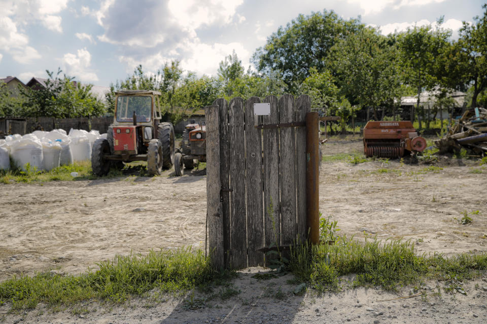 In this picture taken Tuesday, May 21, 2019, an old gate still stands outside a parking area for agricultural equipment in Luncavita, Romania. The Romanian village of Luncavita has benefited greatly from millions in development funds from the European Union, but few of its residents bothered to vote in previous European Parliamentary elections. (AP Photo/Vadim Ghirda)