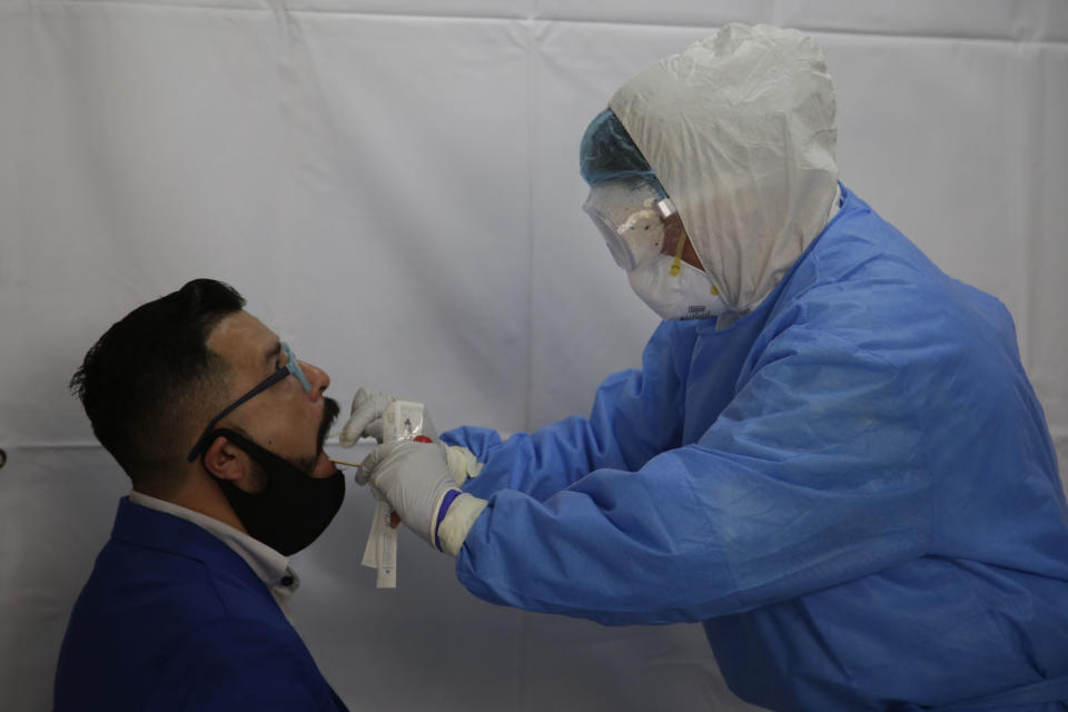 A health worker wears PPE while administering a swab test to detect COVID-19. (Eyepix/SIPA USA/PA Images)