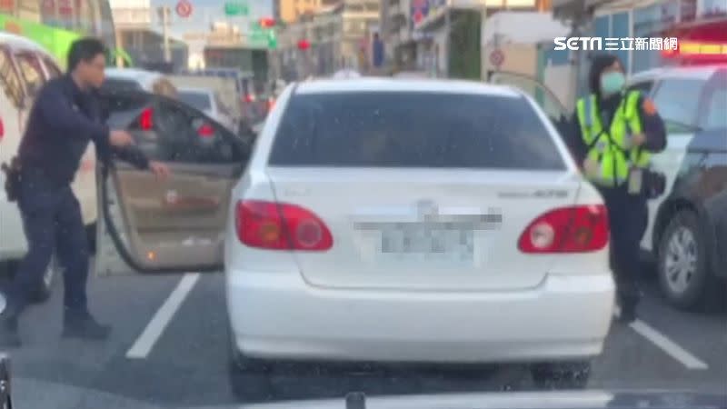 員警包圍轎車，將駕駛帶下車。