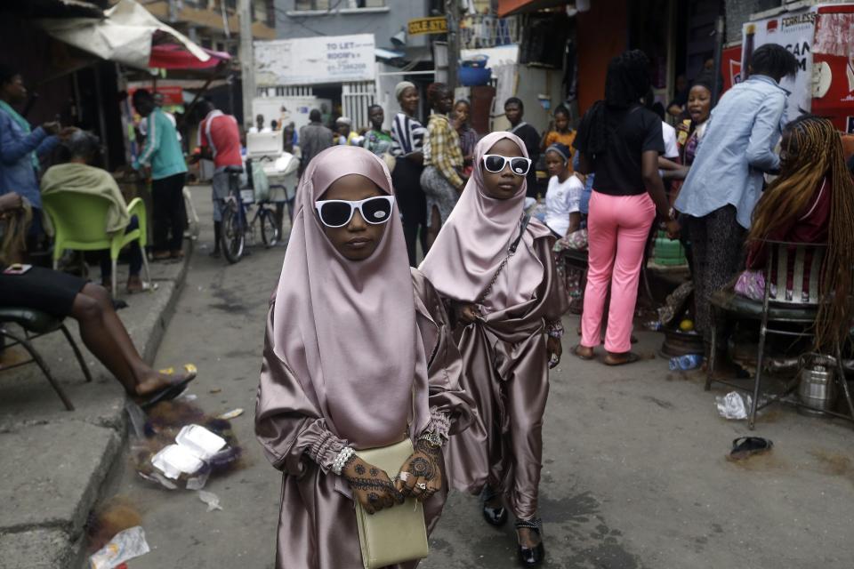 Muslim girls walk down a street after prayers, in Lagos, Nigeria, Friday, July 31, 2020. Small groups of pilgrims performed one of the final rites of the Islamic hajj on Friday as Muslims worldwide marked the start of the Eid al-Adha holiday amid a global pandemic that has impacted nearly every aspect of this year's pilgrimage and celebrations. (AP Photo/Sunday Alamba)