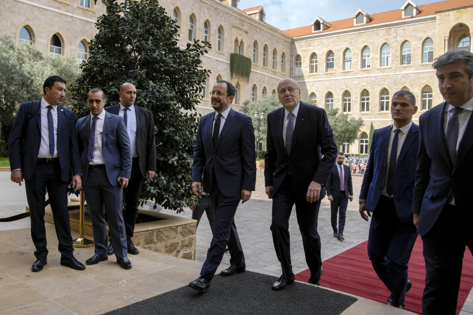 Cyprus' President Nikos Christodoulides, center left, escorted by Lebanese caretaker Prime Minister Najib Mikati, center right, arrives at the government headquarters in Beirut, Lebanon, Monday, April 8, 2024. Christodoulides' visit to Beirut comes after he asked the European Union last week to intervene with Lebanese authorities to stop boatloads of Syrian refugees from heading to the east Mediterranean island nation. Lebanon's caretaker prime minister asked Southern European countries along the Mediterranean Sea to pressure the European Union to help Lebanon deport undocumented migrants. (AP Photo/Bilal Hussein)