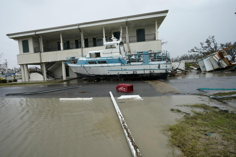 Flooding surrounds a damaged building and boat Friday, Aug. 28, 2020, in Cameron, La., after Hurricane Laura moved through the area Thursday. (AP Photo/David J. Phillip)