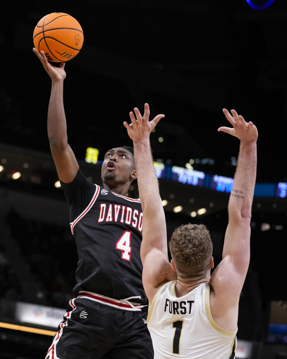 Davidson guard Desmond Watson (4) shoots over Purdue forward Caleb Furst (1) in the second half of an NCAA college basketball game in Indianapolis, Saturday, Dec. 17, 2022. Purdue defeated Davidson 69-61. (AP Photo/Michael Conroy)