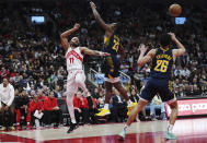 Toronto Raptors forward Bruce Brown (11) passes the ball between Indiana Pacers forward Aaron Nesmith (23) and guard Ben Sheppard (26) during the second half of an NBA basketball game in Toronto on Tuesday, April 9, 2024. (Nathan Denette/The Canadian Press via AP)