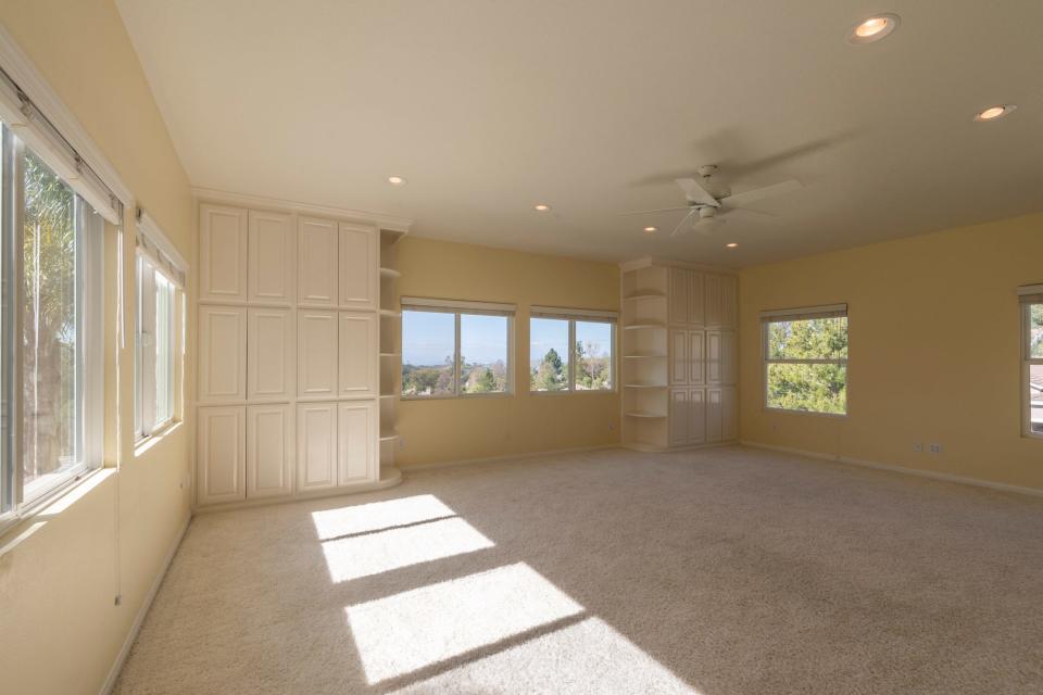 An empty yellow room with cream carpets.