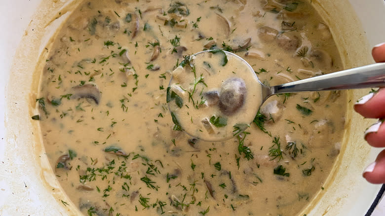 Hand ladling soup over bowl