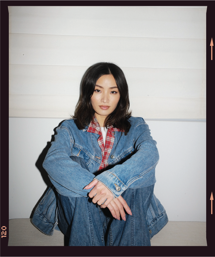 a portrait of anna sawai, sitting with her arms around her knees