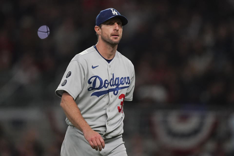 FILE - Los Angeles Dodgers starting pitcher Max Scherzer walks off the field after being relieved in the fifth inning in Game 2 of baseball's National League Championship Series against the Atlanta Braves Sunday, Oct. 17, 2021, in Atlanta. Sometime soon, lockout costs become real: Max Scherzer would forfeit $232,975 for each regular-season day lost, and Gerrit Cole $193,548. Based on last year’s base salaries that totaled just over $3.8 billion, major league players would combine to lose $20.5 million for each day wiped off the 186-day regular-season schedule. (AP Photo/Brynn Anderson, File)