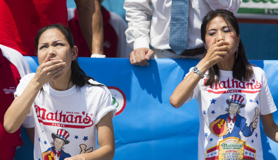 Sonya "The Black Widow" Thomas, left, and Juliet Lee, right, compete during the Nathan's Famous Women's Hot Dog Eating World Championship, Wednesday, July 4, 2012, at Coney Island, in the Brooklyn borough of New York. Thomas won her second consecutive women's competition with a world record breaking 45 downed hot dogs. (AP Photo/John Minchillo)