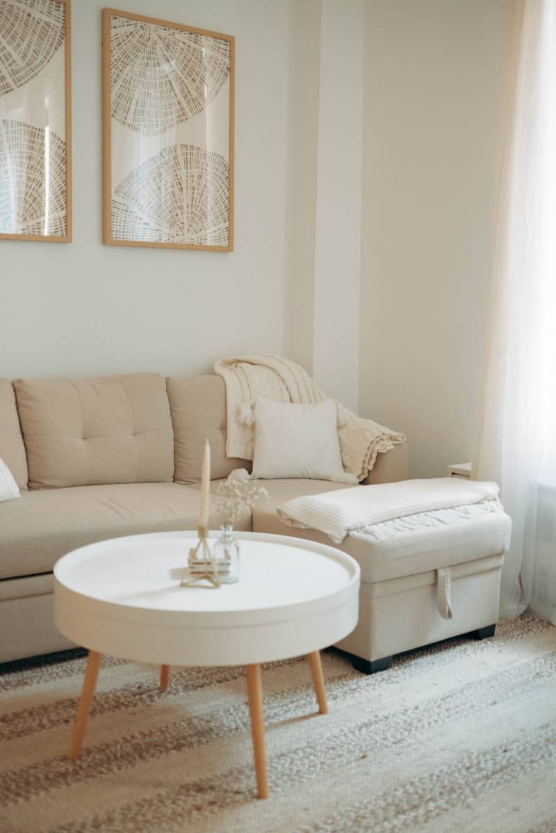 A tan couch next to a white round coffee table