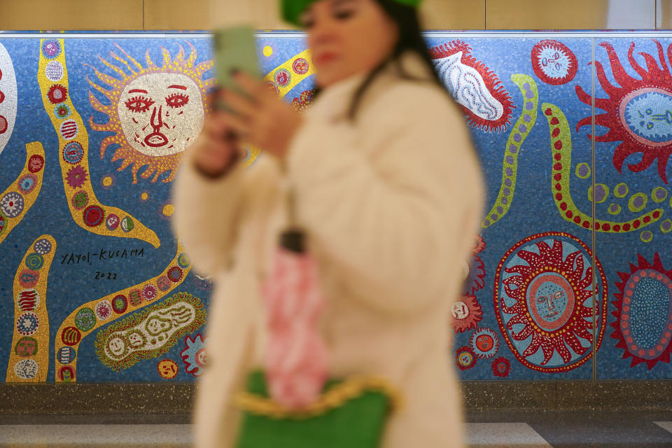 A woman walks past a mural by Yayoi Kusama in the new annex in Grand Central Station in New York, Wednesday, Jan. 25, 2023. After years of delays and massive cost overruns, one of the world's most expensive railway projects on Wednesday began shuttling its first passengers between Long Island to a new annex to New York City's iconic Grand Central Terminal. (AP Photo/Seth Wenig)