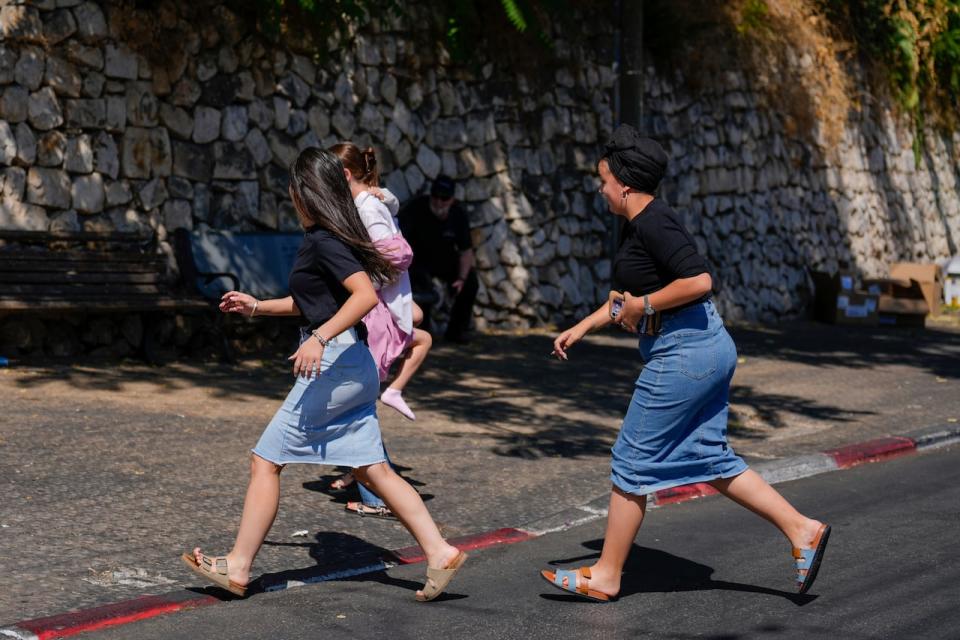 People run to take cover as a siren sounds a warning of incoming rockets fired from Lebanon, in Safed, northern Israel, on Thursday, Sept. 26, 2024.