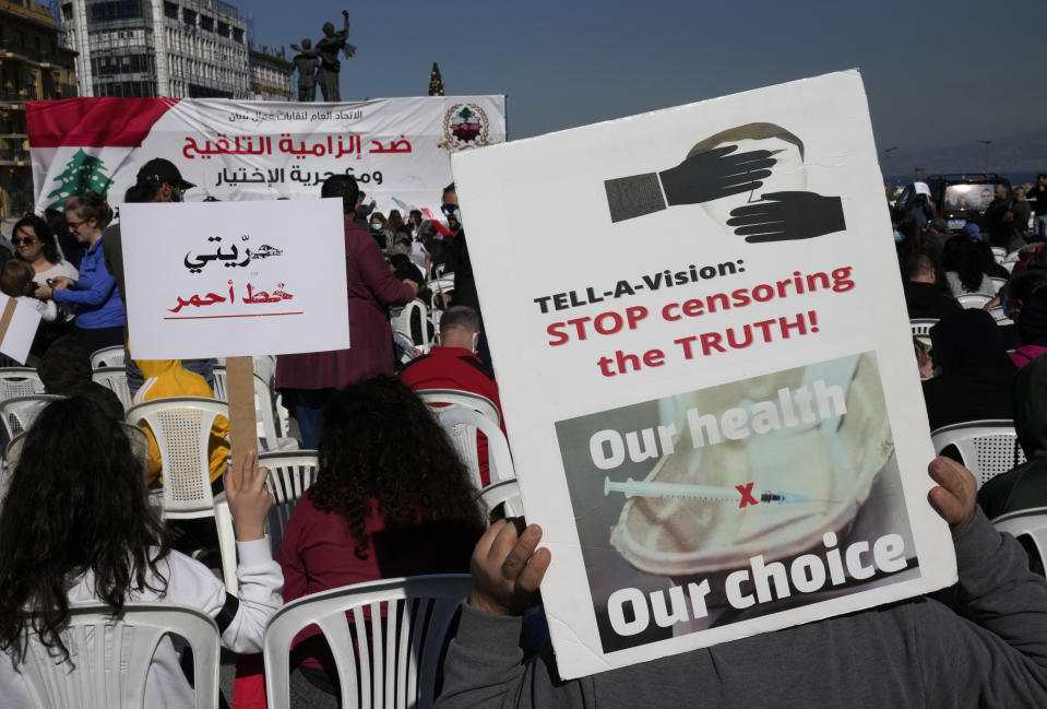 Protesters hold placards during a rally to protest measures imposed against people who are not vaccinated, in Beirut, Lebanon, Saturday, Jan. 8, 2022. Vaccination is not compulsory in Lebanon but in recent days authorities have become more strict in dealing with people who are not inoculated or don't carry a negative PCR test. The Arabic placard, left, reads:"MY freedom is red line."(AP Photo/Hussein Malla)