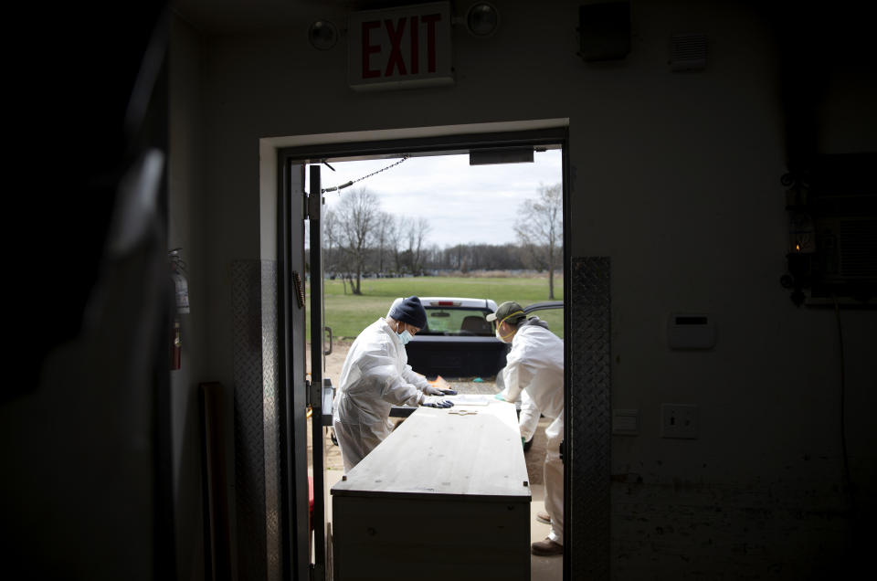 Gravedigger Thomas Cortez, left, helps load a casket of someone who is presumed to have died from coronavirus as they keep pace with a surge in burials at Mount Richmond Cemetery in the Staten Island borough of New York, Tuesday, April 7, 2020. "It's sad, it's sad, and I feel sorry because they want to see. They can't. They have to be in the car and can't go and cry where it has to be," said Cortez of family members who must remain in their cars for burials and can't approach the grave. (AP Photo/David Goldman)