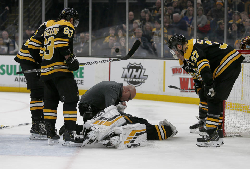 FILE - In this Jan. 19, 2019, file photo, Boston Bruins goaltender Tuukka Rask (40) is attended to on the ice as teammates Zdeno Chara, Brad Marchand (63) and Patrice Bergeron (37) look on after Rask sustained a concussion in a collision with New York Rangers center Filip Chytil during the first period of an NHL hockey game in Boston. The goal counted, Chytil faced no repercussions and Rask was concussed. Those kinds of collisions are happening at an alarming rate over the past couple of seasons, leading to an increase in goaltender concussions. (AP Photo/Mary Schwalm, File)