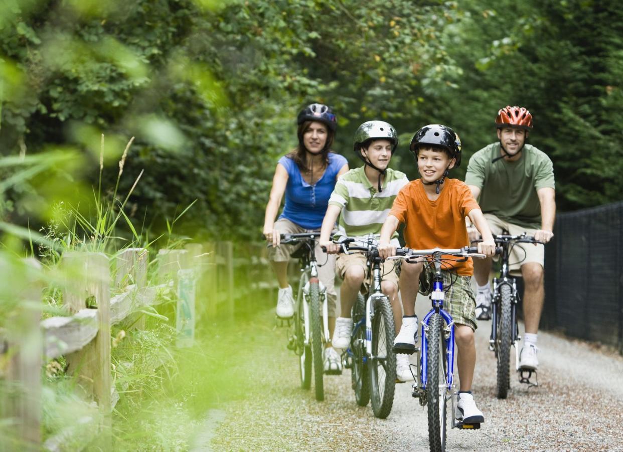 mom, dad and two kids cycling down path in park