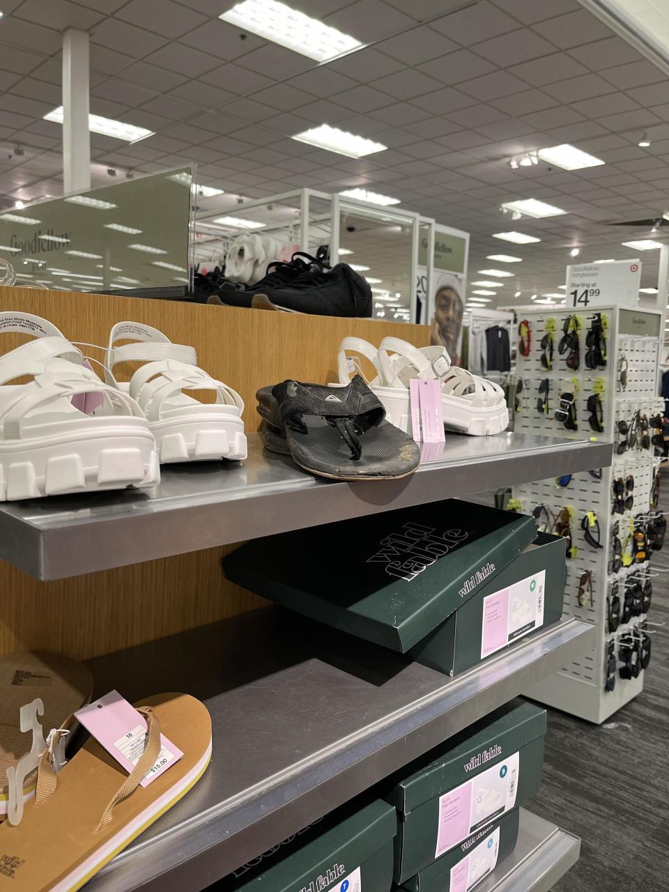 Shelves stocked with various shoes and shoeboxes in a retail store setting and one person's used dirty flop-flop sitting on the shelf