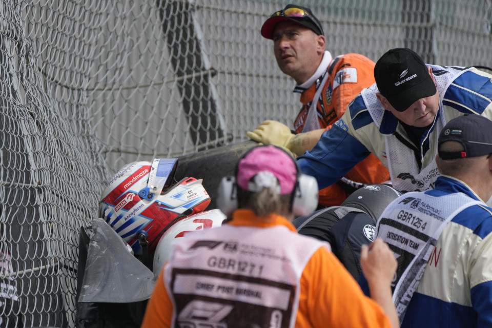 Alfa Romeo driver Guanyu Zhou of China, left, receives medical treatment after he was involved in a crash at the start of the British Formula One Grand Prix at the Silverstone circuit, in Silverstone, England, Sunday, July 3, 2022. (AP Photo/Frank Augstein)