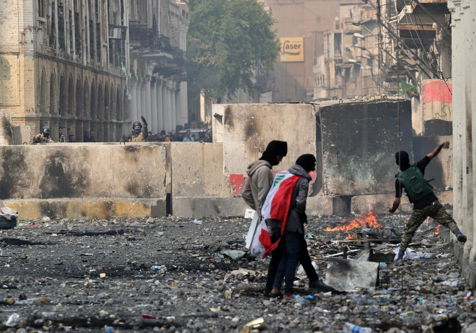 Anti-government protesters throw Molotov cocktails and stones while security forces close Rasheed Street during clashes in Baghdad, Iraq, Wednesday, Nov. 27, 2019. Several protesters were killed by security forces who fired live rounds in Baghdad and southern Iraq amid ongoing violence and days of sit-ins and road closures, Iraqi officials said Wednesday. (AP Photo/Khalid Mohammed)