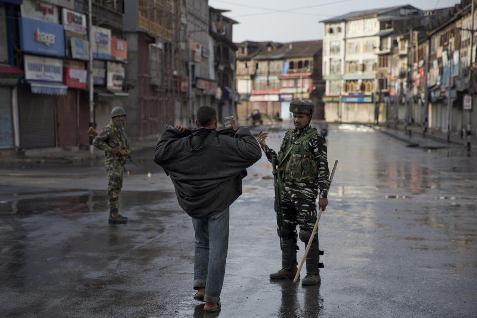 An Indian Paramilitary soldier orders a Kashmiri to lift his robe before frisking him during curfew in Srinagar, Indian controlled Kashmir, Thursday, Aug. 8, 2019. The lives of millions in India's only Muslim-majority region have been upended since the latest, and most serious, crackdown followed a decision by New Delhi to revoke the special status of Jammu and Kashmir and downgrade the Himalayan region from statehood to a territory. Kashmir is claimed in full by both India and Pakistan, and rebels have been fighting Indian rule in the portion it administers for decades. (AP Photo/Dar Yasin)