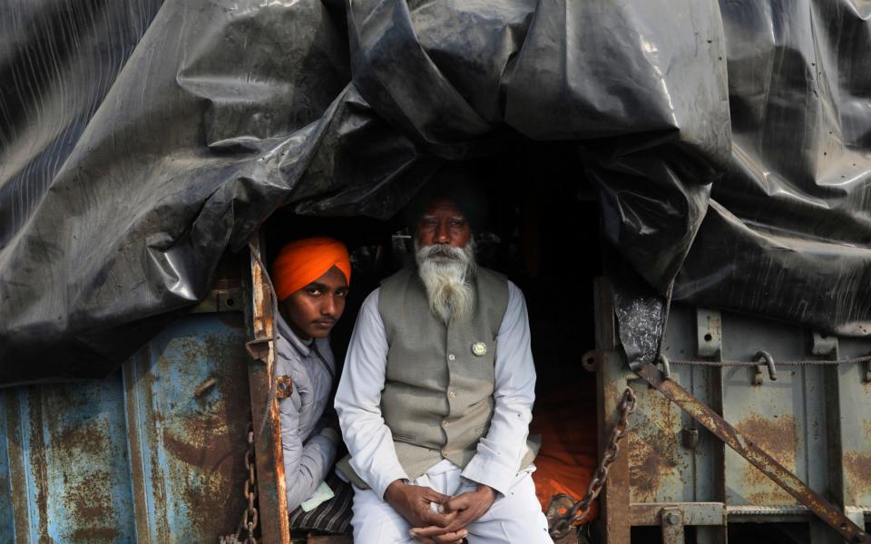An elderly Indian Farmer sits with his grandson at the back of their trailer as they block a highway at the Delhi- Haryana border at the outskirts of New Delhi, India - AP/AP